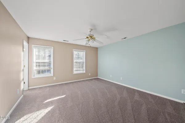 a spacious bedroom with a bed a chandelier and a window