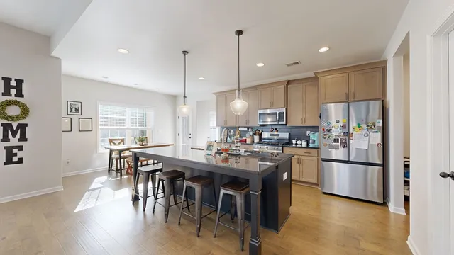 a kitchen with stainless steel appliances granite countertop a refrigerator a sink dishwasher a stove and white cabinets with wooden floor