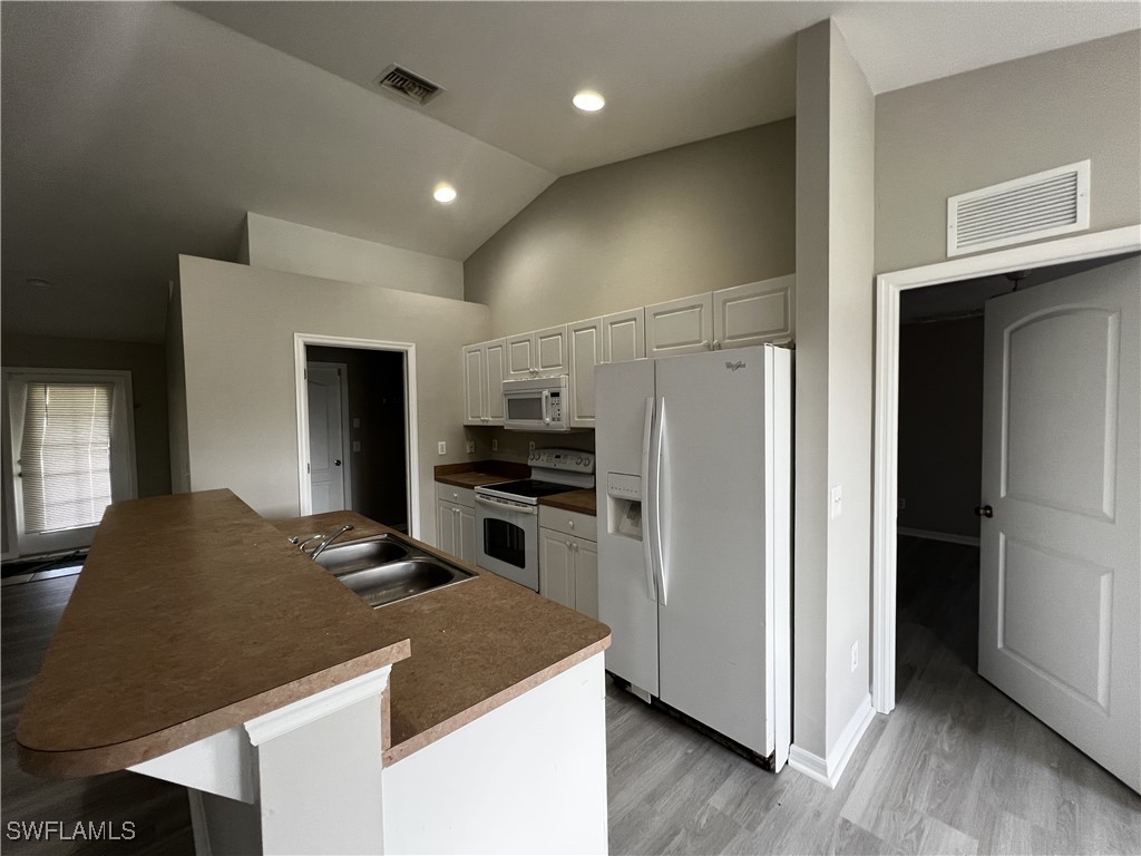 672 Homestead Road South Lehigh Acres, FL 33974 - Photo 5 of 35 a kitchen with kitchen island white cabinets and stainless steel appliances