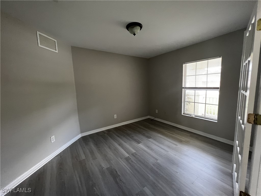 672 Homestead Road South Lehigh Acres, FL 33974 - Photo 8 of 35 wooden floor in an empty room with a window