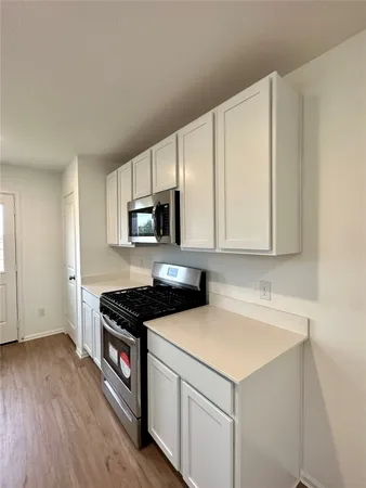 a kitchen with stainless steel appliances a stove a microwave a sink and cabinets
