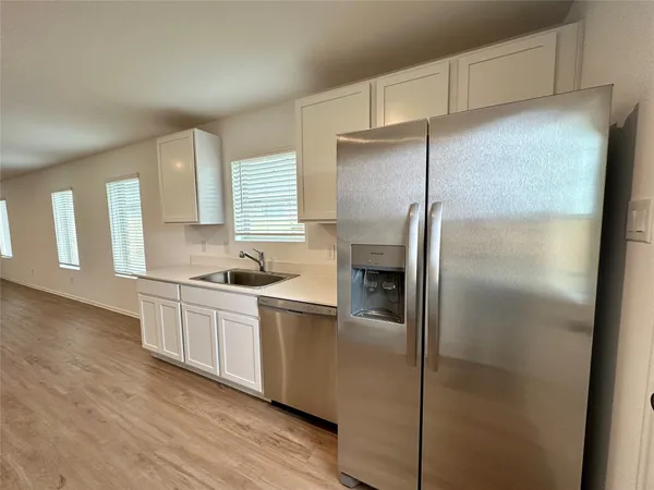 a kitchen with stainless steel appliances granite countertop a refrigerator a sink and white cabinets