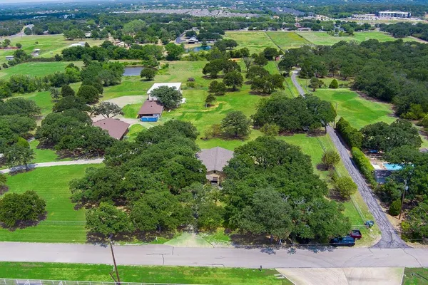 an aerial view of residential houses with outdoor space and trees