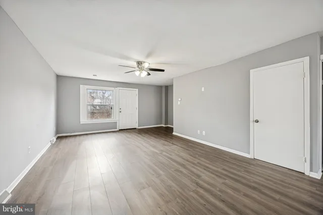 an empty room with wooden floor chandelier and windows