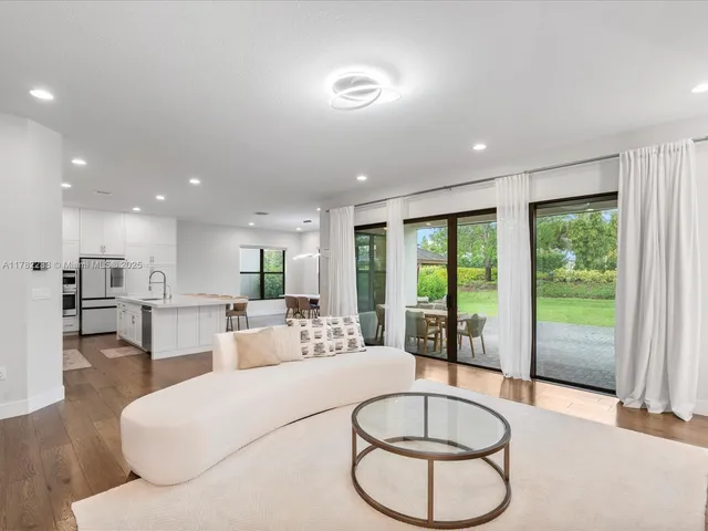 a kitchen with stainless steel appliances a stove a sink a refrigerator white cabinets and wooden floor