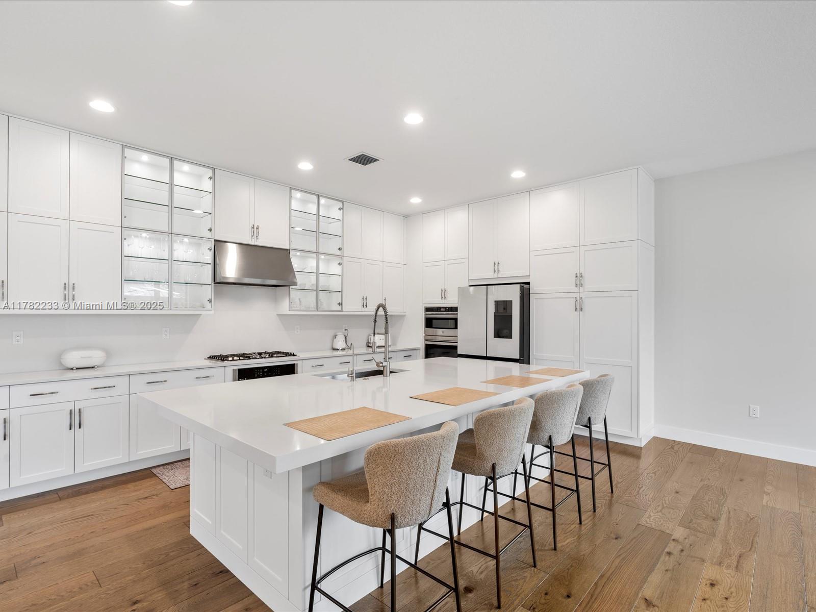 20324 Castle Stuart Avenue Boca Raton, FL 33434 - Photo 16 of 79 a kitchen with stainless steel appliances a stove a sink a refrigerator white cabinets and wooden floor