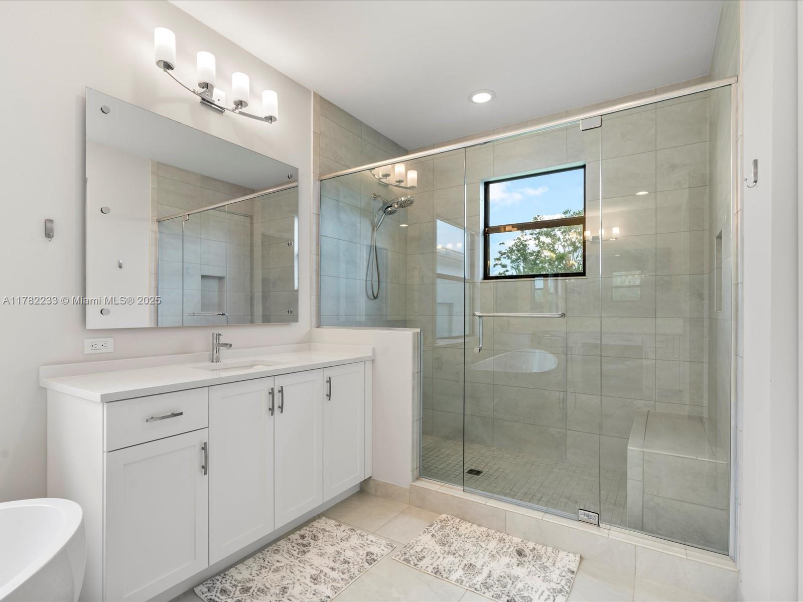 20324 Castle Stuart Avenue Boca Raton, FL 33434 - Photo 41 of 79 a bathroom with a shower sink and mirror