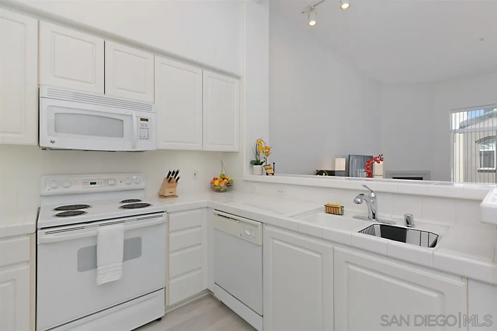 9237 Regents Road, Unit K401 La Jolla, CA 92037 - Photo 12 of 25 a kitchen with white cabinets and white appliances