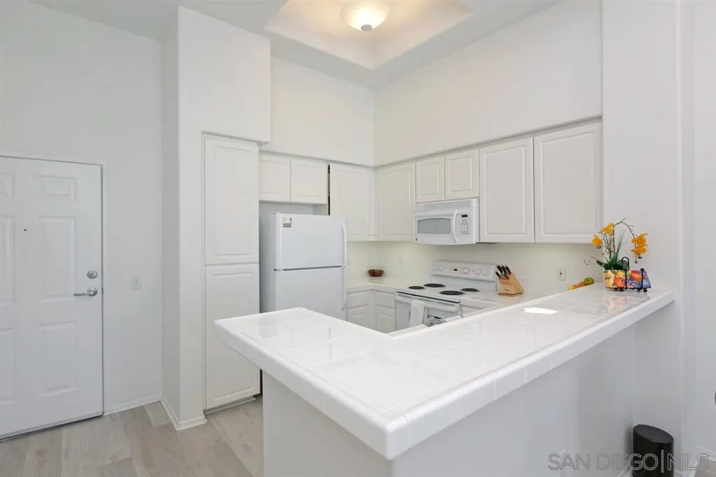 9237 Regents Road, Unit K401 La Jolla, CA 92037 - Photo 14 of 25 a kitchen with a sink a stove a refrigerator and white cabinets
