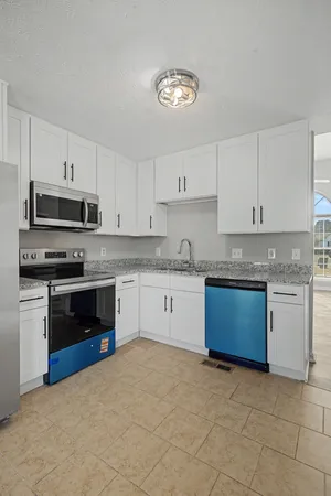 a kitchen with granite countertop a stove a sink dishwasher and a refrigerator