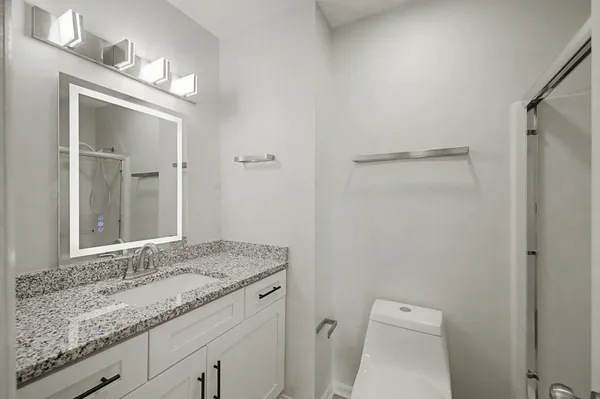 a bathroom with a granite countertop sink a toilet and a mirror