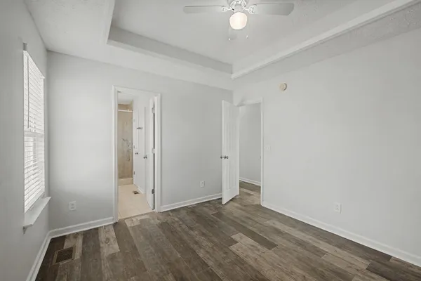 an empty room with wooden floor cabinet and windows