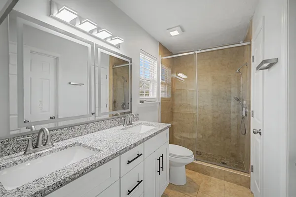 a bathroom with a granite countertop sink a toilet a mirror and shower