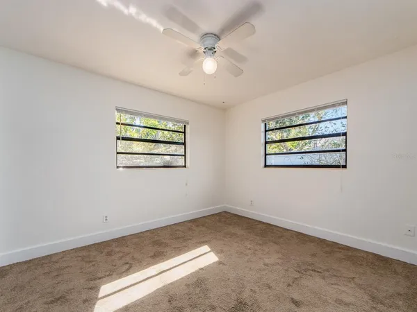 an empty room with windows and ceiling fan
