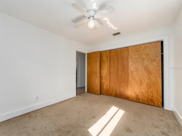 an empty room with a window and a ceiling fan