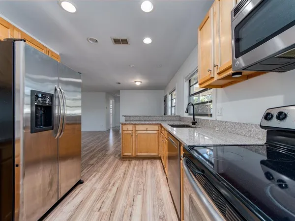 a kitchen with stainless steel appliances granite countertop a lot of counter space and wooden floors