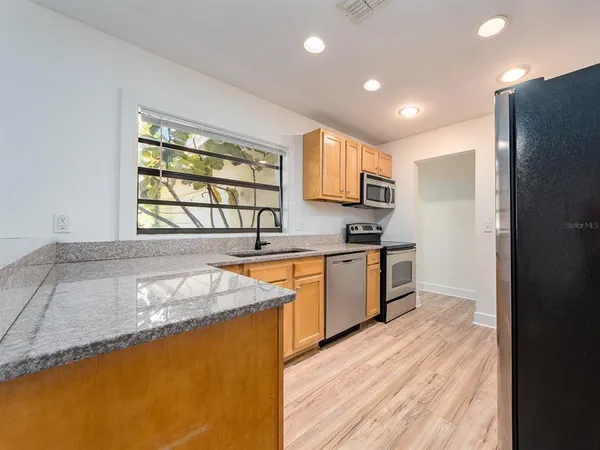 a kitchen with granite countertop a refrigerator and a stove top oven