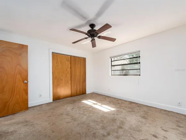 an empty room with windows and fan