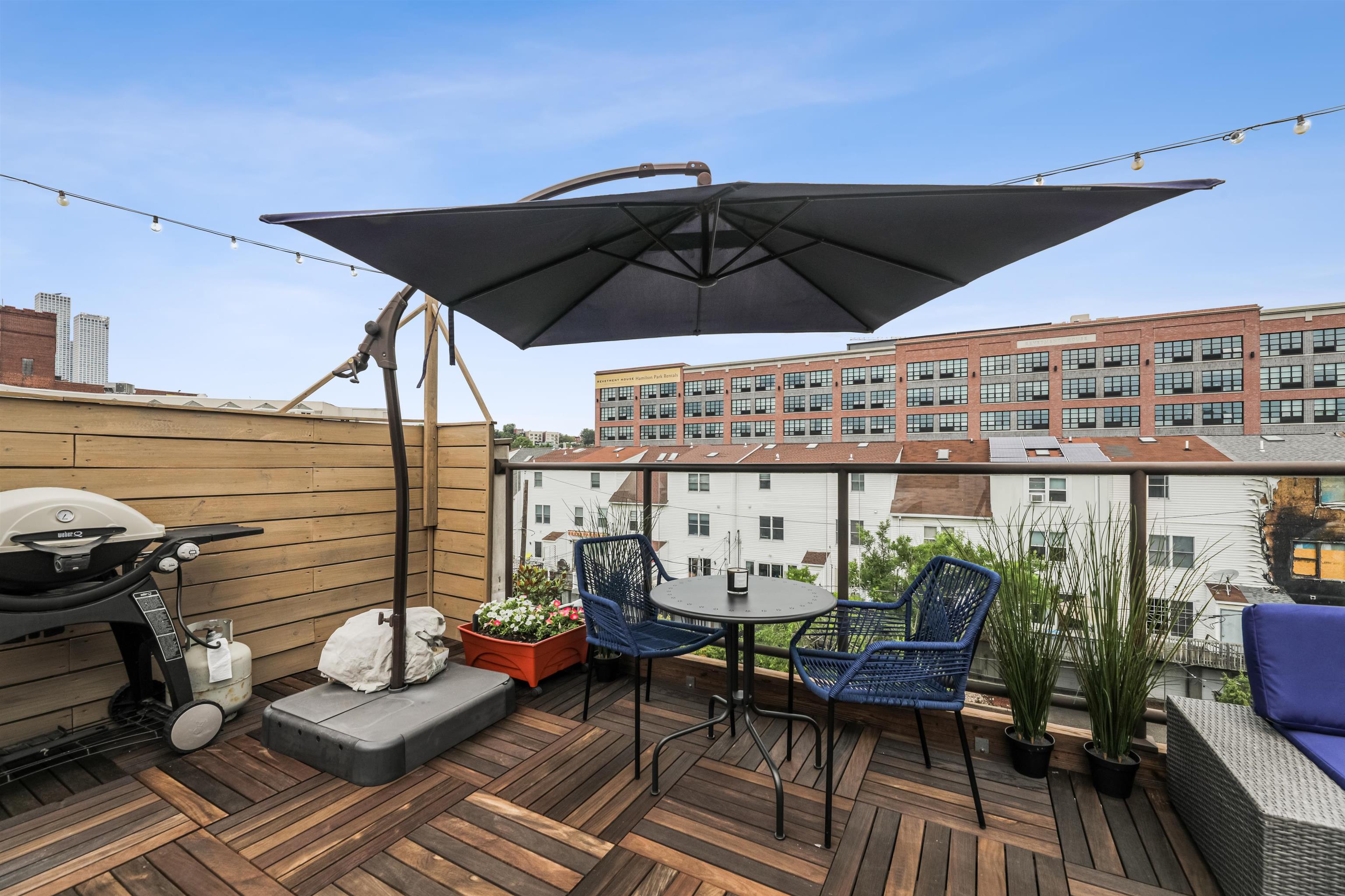 310 9th Street Jersey City, NJ 07302 - Photo 30 of 34 a roof deck with table and chairs under an umbrella