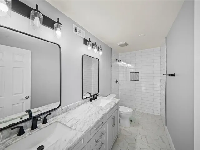 a bathroom with a double vanity sink mirror and toilet