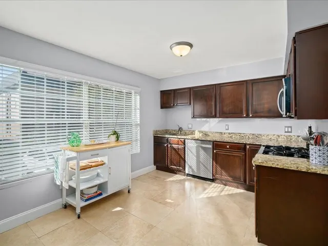 a kitchen with granite countertop a stove a sink a microwave and wooden cabinets