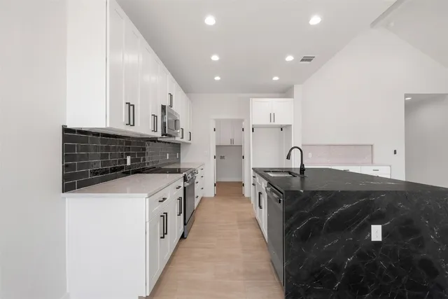 a large kitchen with stainless steel appliances granite countertop a large counter top and a refrigerator