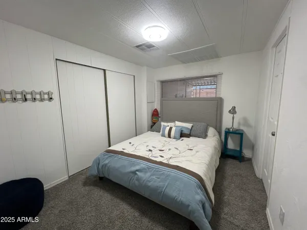 a bedroom with a bed and a lamp on the dresser
