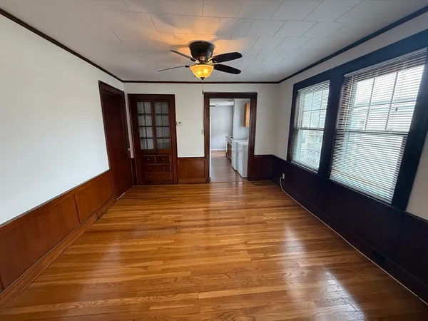 a view of empty room with wooden floor and fan
