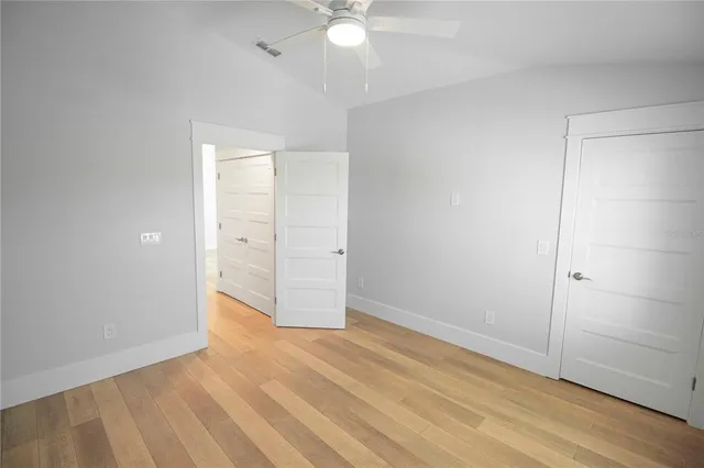 an empty room with wooden floor and fan