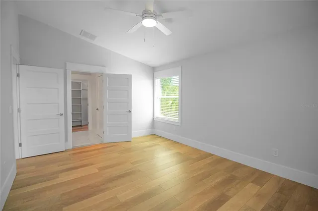 a view of empty room with wooden floor and fan