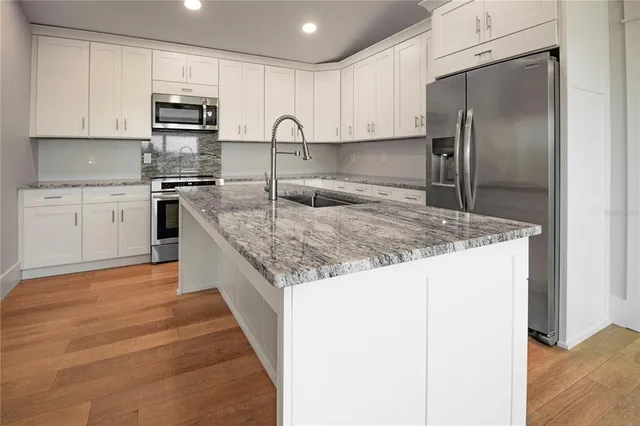 a kitchen with stainless steel appliances granite countertop a sink a stove and a refrigerator