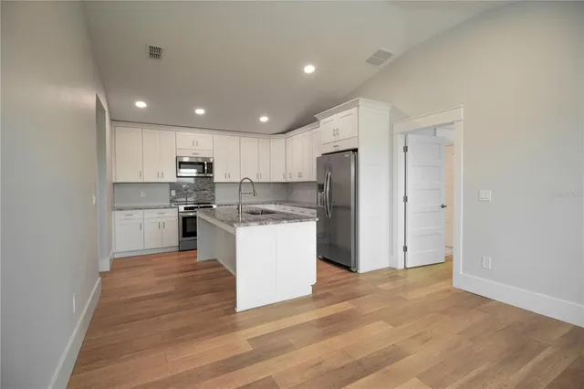 a kitchen with a refrigerator and white cabinets