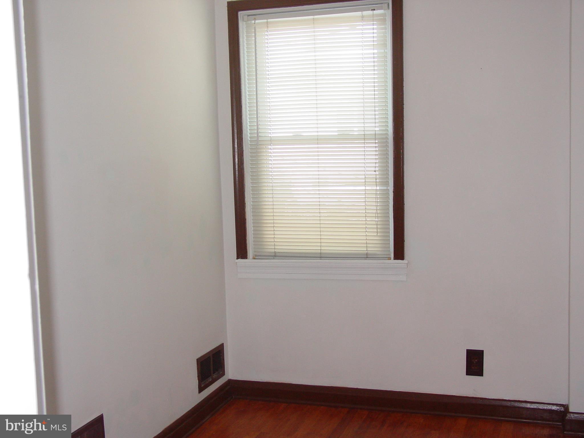 7406 Kirtley Road Baltimore, MD 21222 - Photo 10 of 21 a view of an empty room with wooden floor and a window