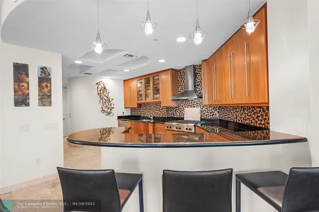 a kitchen with stainless steel appliances granite countertop a sink a stove a refrigerator a microwave oven with white cabinets and wooden floor