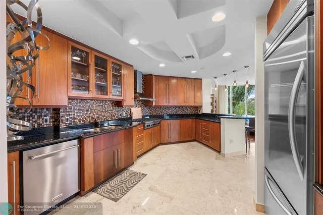 a large kitchen with stainless steel appliances granite countertop a refrigerator and a sink
