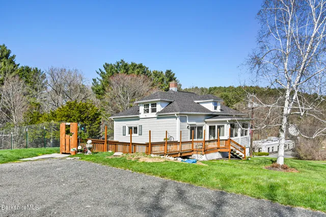 a view of a white house with a big yard and large trees