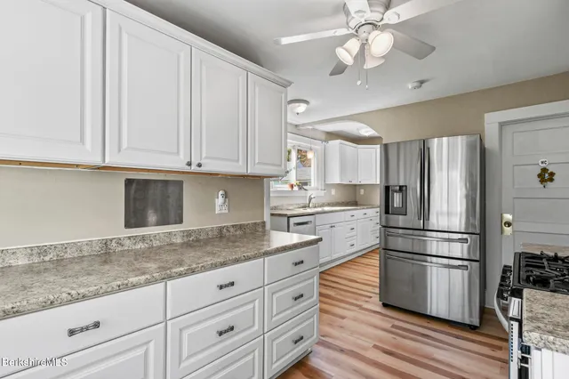 a kitchen with granite countertop white cabinets and stainless steel appliances