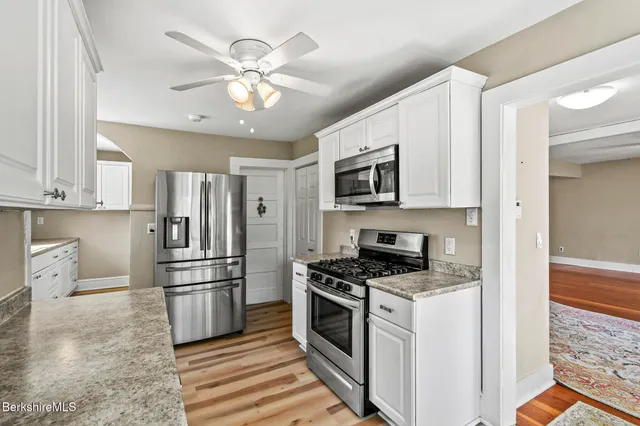a kitchen with stainless steel appliances a stove a refrigerator cabinets and a chandelier
