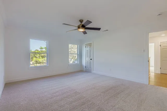 an empty room with windows and fan