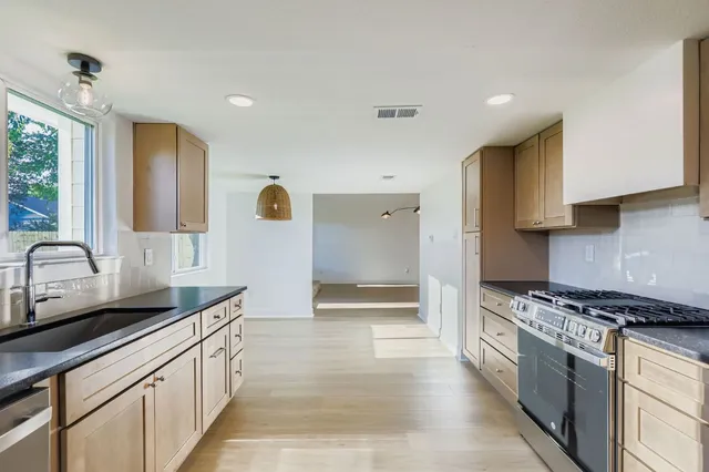 a kitchen with stainless steel appliances a sink stove and cabinets