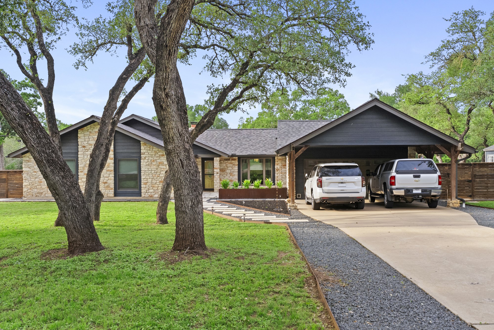 2802 Robin Road Manchaca, TX 78652 - Photo 6 of 40 Stone-clad facade with dark siding accents, a prominent carport with wood supports, and a gray shingle roof