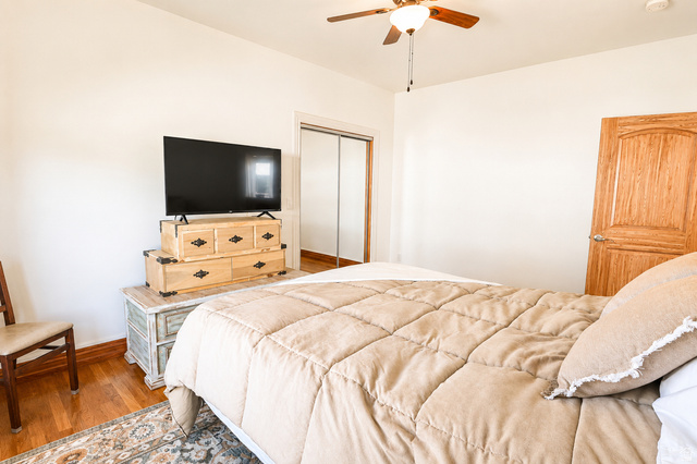 1055 North 1000 East Mapleton, UT 84664 - Photo 44 of 112 Bedroom featuring wood-finish flooring, a ceiling fan with integrated lighting, and a solid wood paneled door