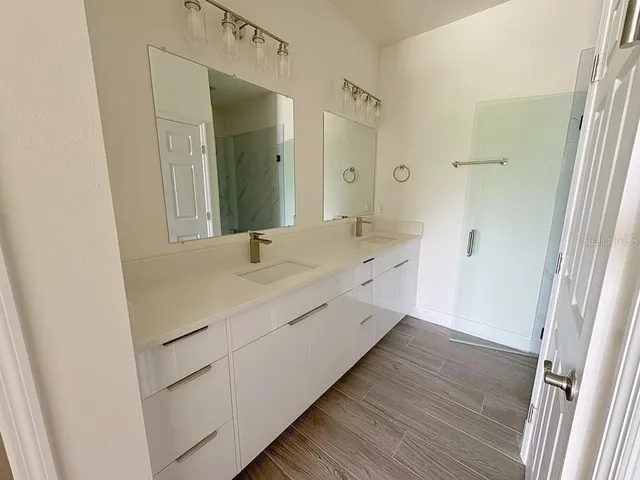 a bathroom with a double vanity sink and mirror with shower