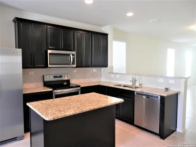 a kitchen with stainless steel appliances kitchen island granite countertop a refrigerator and a stove top oven