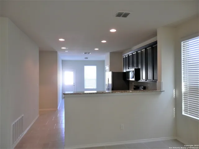 a view of an empty room and a kitchen
