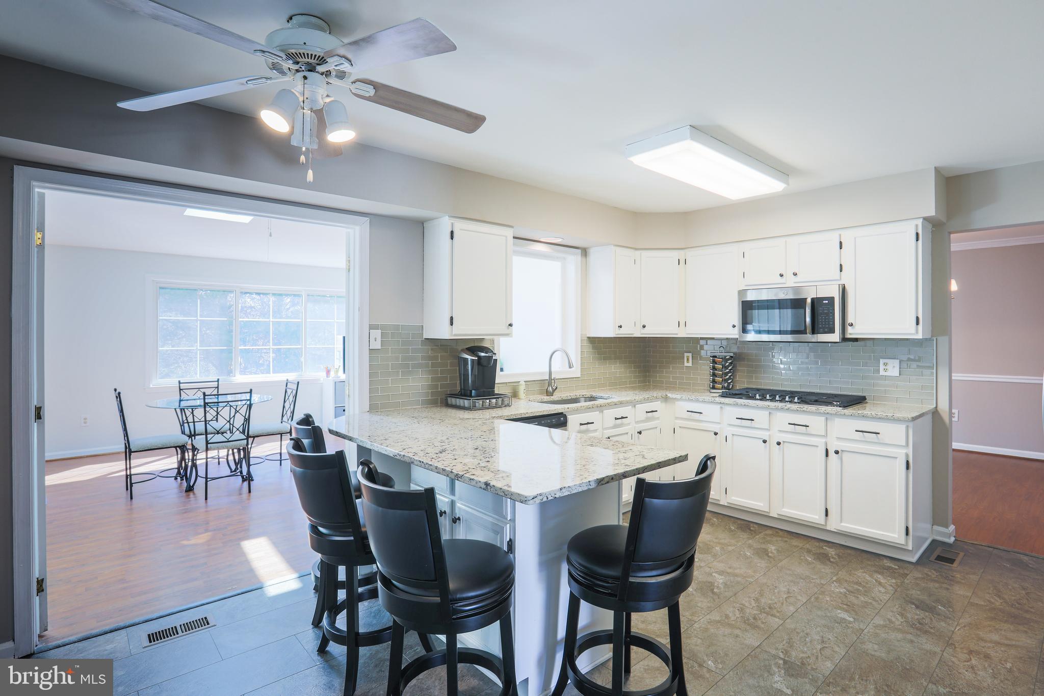 9547 Hallhurst Road Baltimore, MD 21236 - Photo 13 of 49 a kitchen with stainless steel appliances granite countertop a dining table chairs stove refrigerator and cabinets