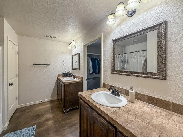 a bathroom with a granite countertop sink a light fixture and a mirror