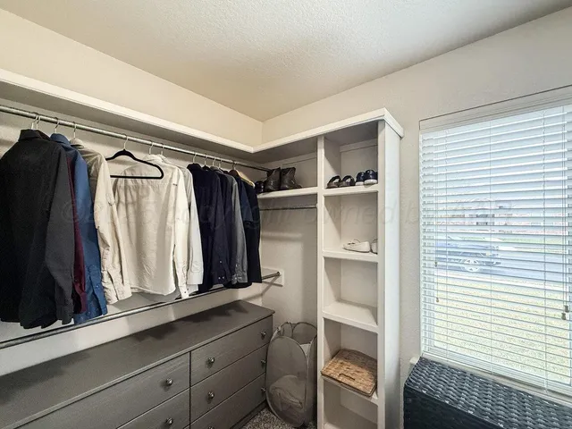 a view of walk in closet with clothes and shoes