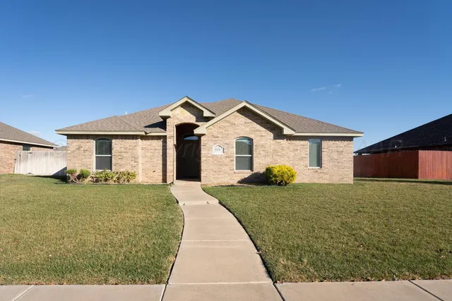 a front view of house with yard and trees in the background