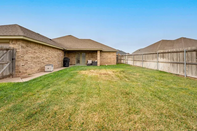 a view of a house with a yard and wooden fence